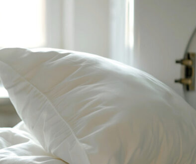 A crisp white pillow rests against freshly laundered bedding, glowing softly in natural daylight near an open front-loading washer. The scene radiates freshness, comfort, and care—an everyday moment elevated by the expertise of Park Avenue Laundry, proudly serving Bemidji, Minnesota for over 40 years.