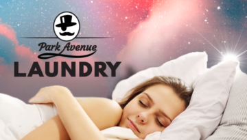 woman sleeps in fluffy beding under galaxy sky with park avenue laundry in bemidji logo