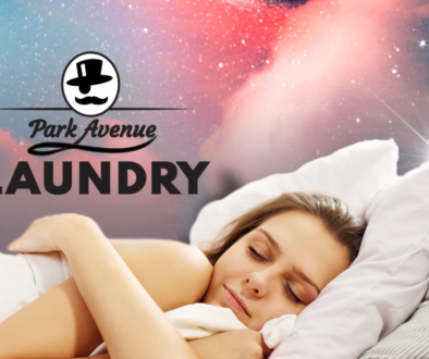 woman sleeps in fluffy beding under galaxy sky with park avenue laundry in bemidji logo